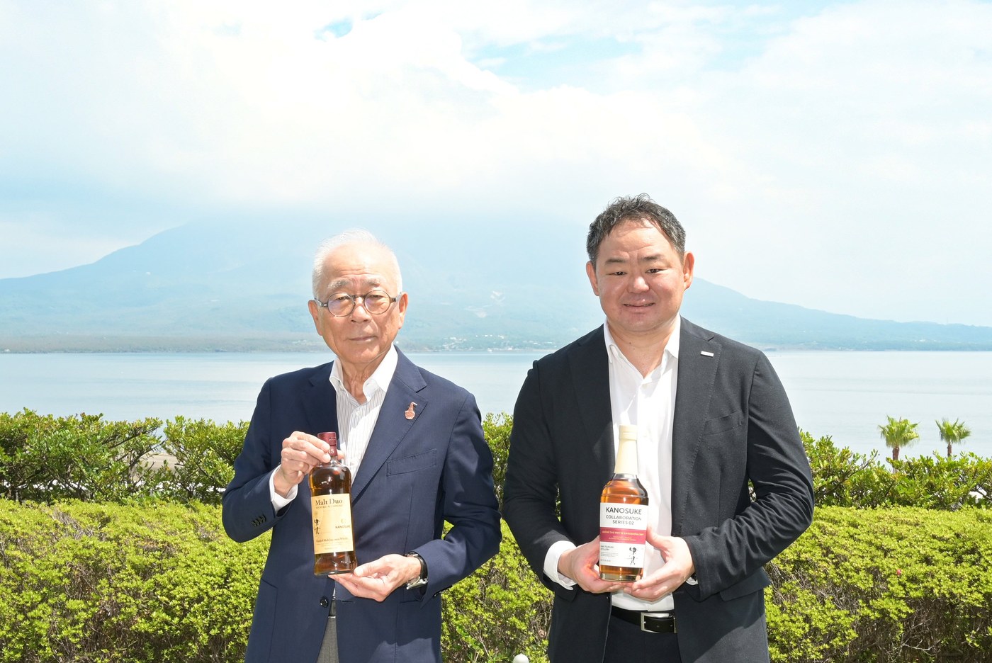 本坊酒造の本坊和人社長と小正嘉之助蒸溜所の小正芳嗣社長が、それぞれのボトルを持つ写真